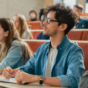 Students seated in a lecture hall, engaged in a lesson from the instructor. Students seated in a lecture hall, engaged in a lesson from the instructor.